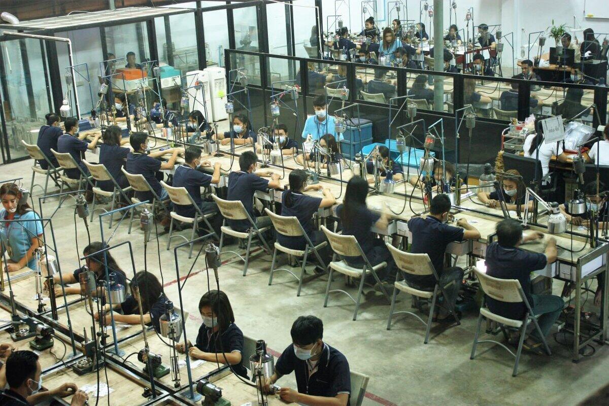 Overhead view of jewelry manufacturing floor with dozens of workers at polishing stations
